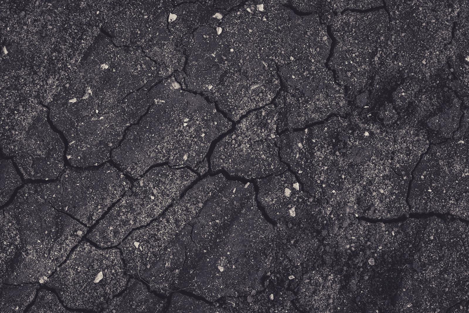 Close-up of cracked earth with dark tones, showcasing natural textures and patterns.